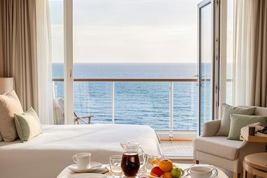 Helle Balkonkabine mit gedecktem Frühstückstisch und Blick auf das Meer